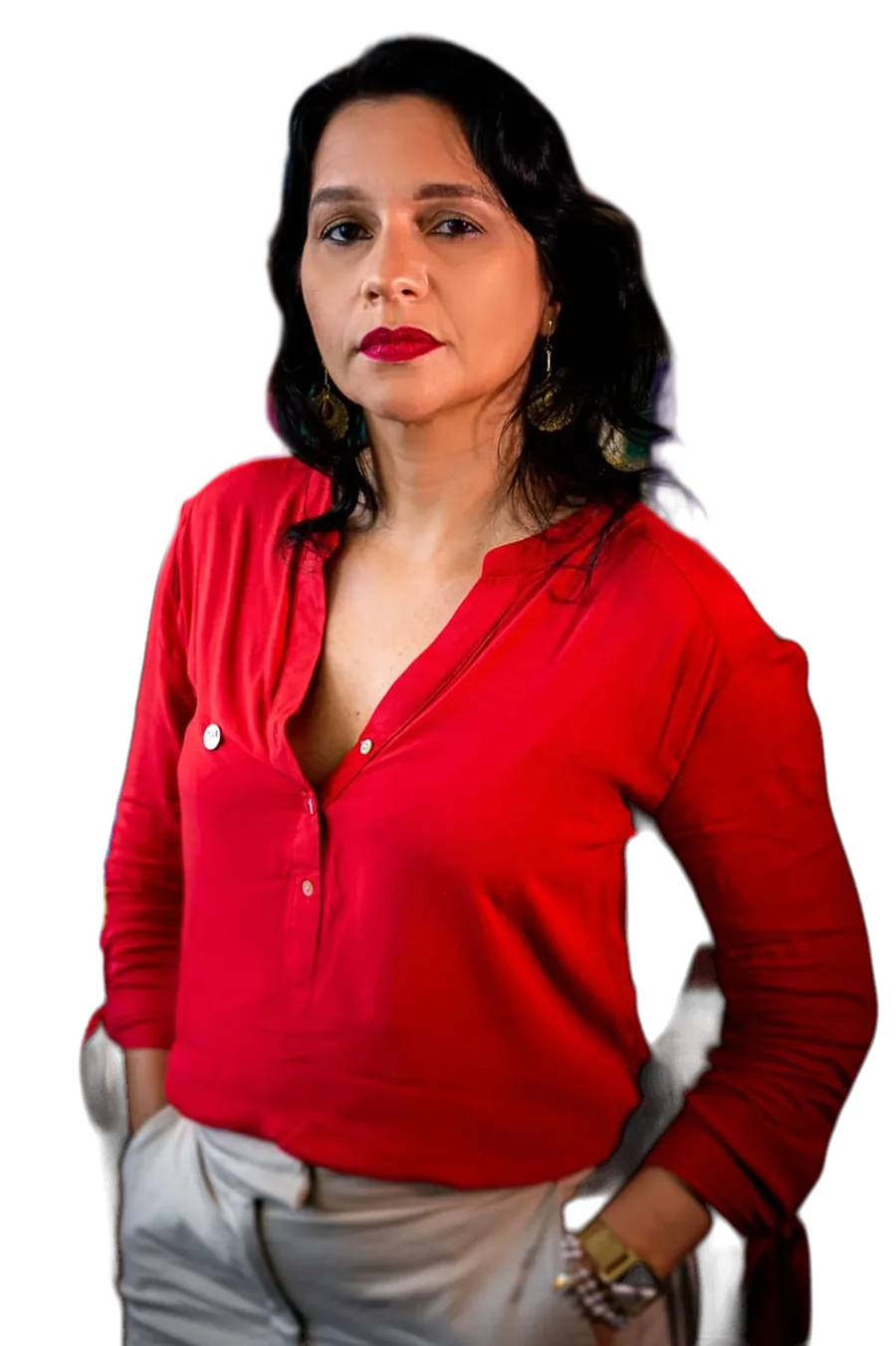Viviane Gomes de pé, em penumbra, de blusa vermelha e com a mão no bolso, olhando de frente